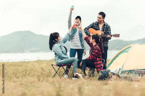 Group of Friends having fun together and drinking at camping near the lake and mountian back.