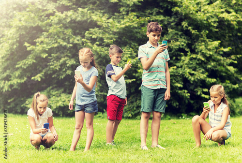 childhood, augmented reality, internet addiction, technology and people concept - group of kids or friends with smartphones playing game in summer park © Syda Productions
