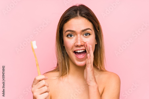 Young caucasian woman holding a teeth brush isolated shouting excited to front.