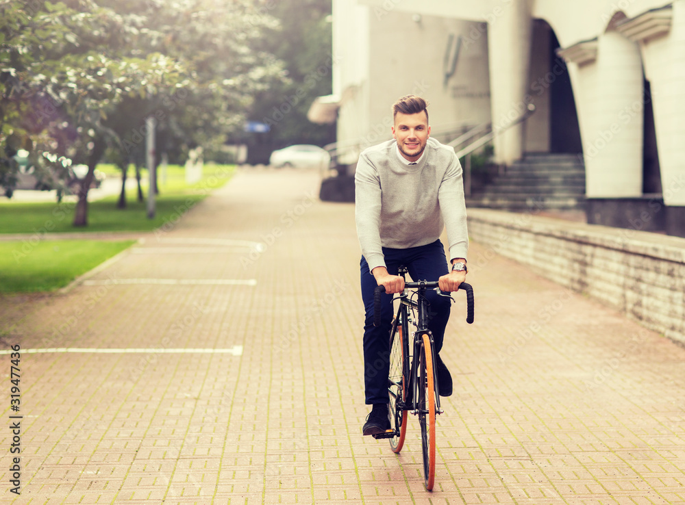 lifestyle, transport and people concept - young man riding bicycle on city street