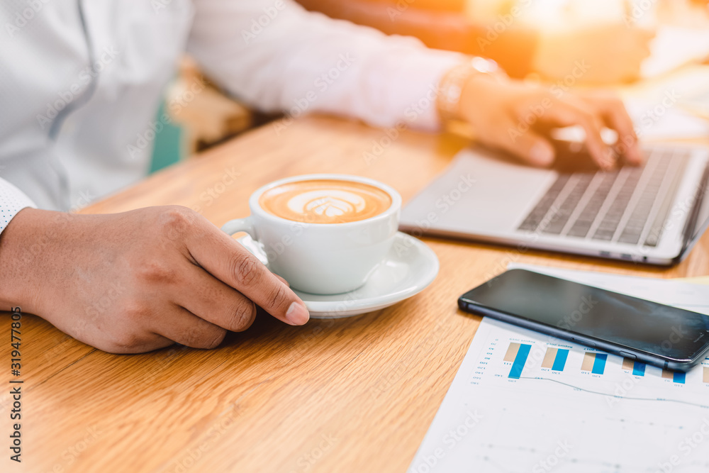 Businessman hold cup of coffee. A cup of coffee is on the table near phone. Businessman hold cup of coffee. A cup of coffee is on the table near phone.