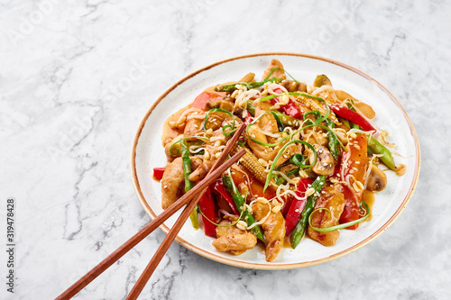 Chicken Chop Suey in white plate on marble background. Chop Suey is American Chinese cuisine dish with different stir fried vegetables, chicken meat and sauces. Copy space. American food. photo