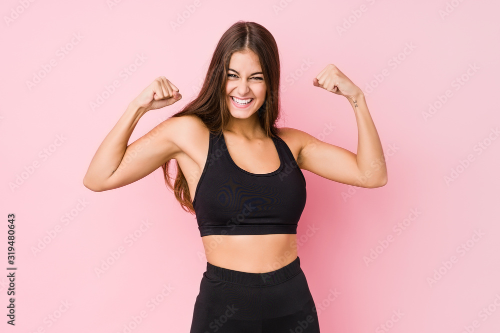 Young caucasian fitness woman doing sport isolated showing strength gesture with arms, symbol of feminine power