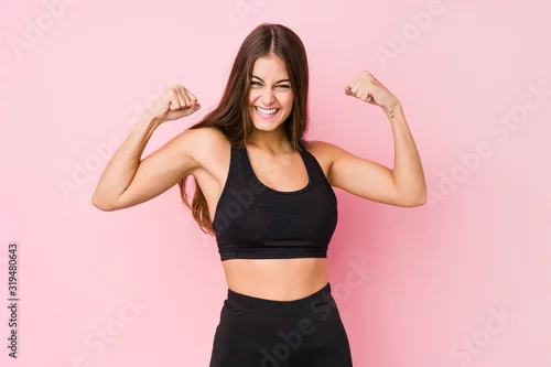 Obraz Young caucasian fitness woman doing sport isolated showing strength gesture with arms, symbol of feminine power