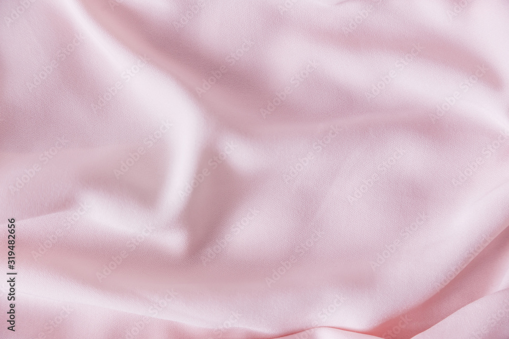 Pink wrinkled silk fabric. The pink fabric is laid out waves. Pink fabric background or texture. Pink wrinkled silk fabric. The pink fabric is laid out waves. Pink fabric background or texture.
