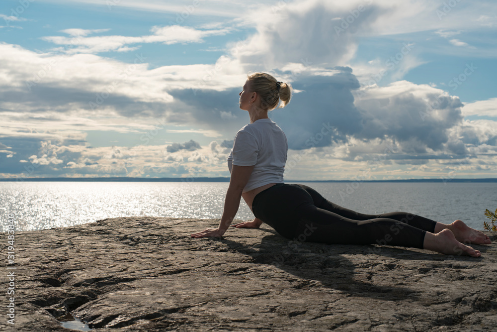 Woman practicing Yoga, meditation or stretching close to water on Cliff doing different poses on beautiful landscape. Concept of finding ideal calm meditation place, finding yourself and Healthy Life. Woman practicing Yoga, meditation or stretching close to water on Cliff doing different poses on beautiful landscape. Concept of finding ideal calm meditation place, finding yourself and Healthy Life.