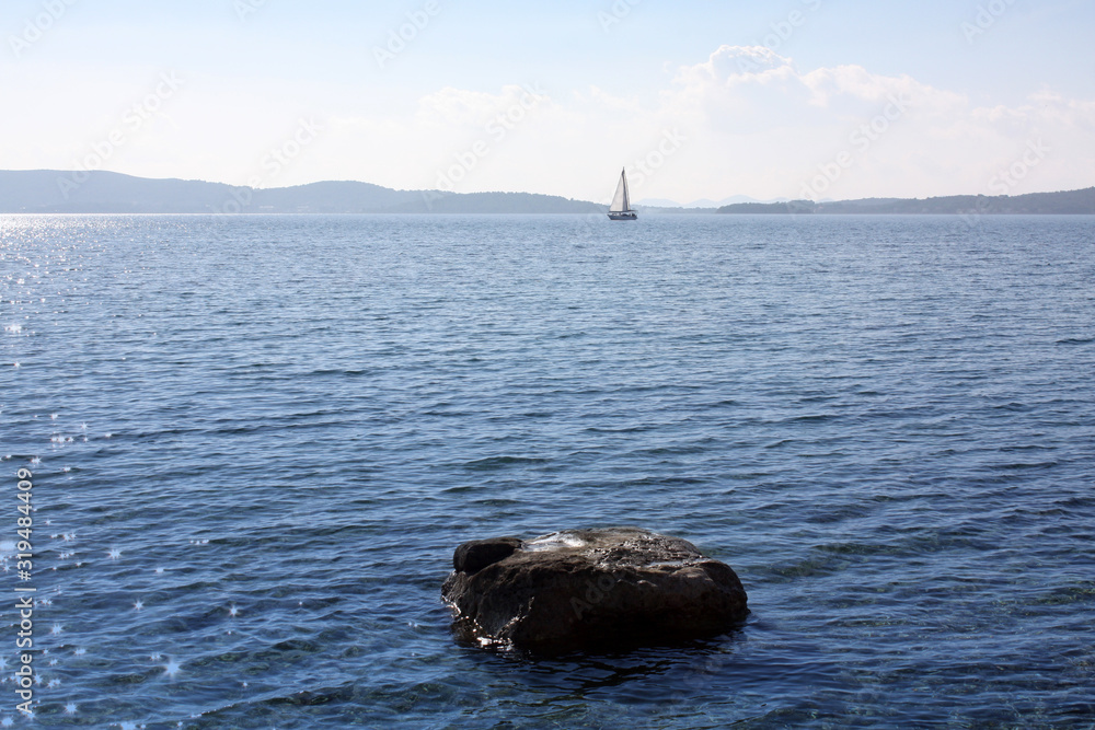 Boat with white sail in Adriatic Sea.