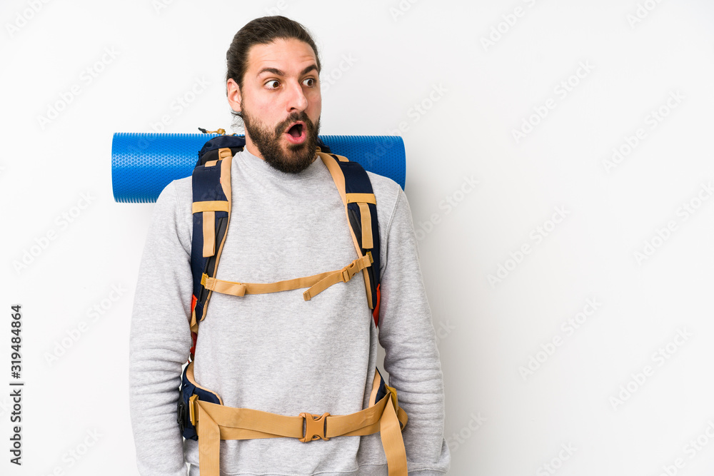 Young backpacker man isolated on a white background being shocked because of something she has seen.