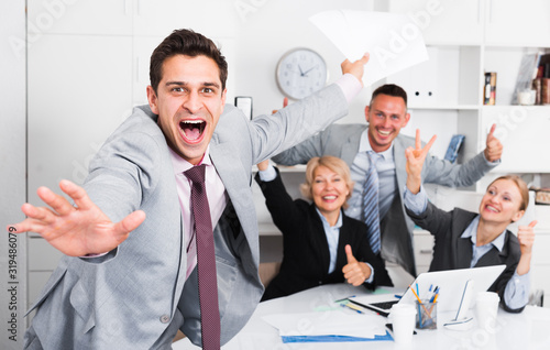 Excited businessman with happy team celebrating victory photo