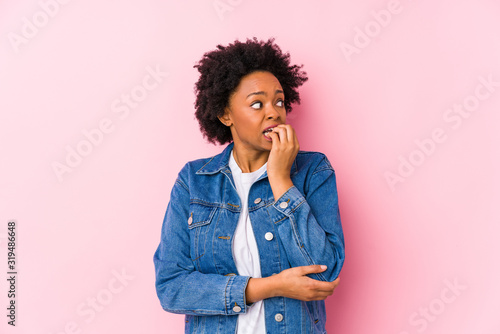 Young african american woman against a pink backgroound isolated biting fingernails, nervous and very anxious.