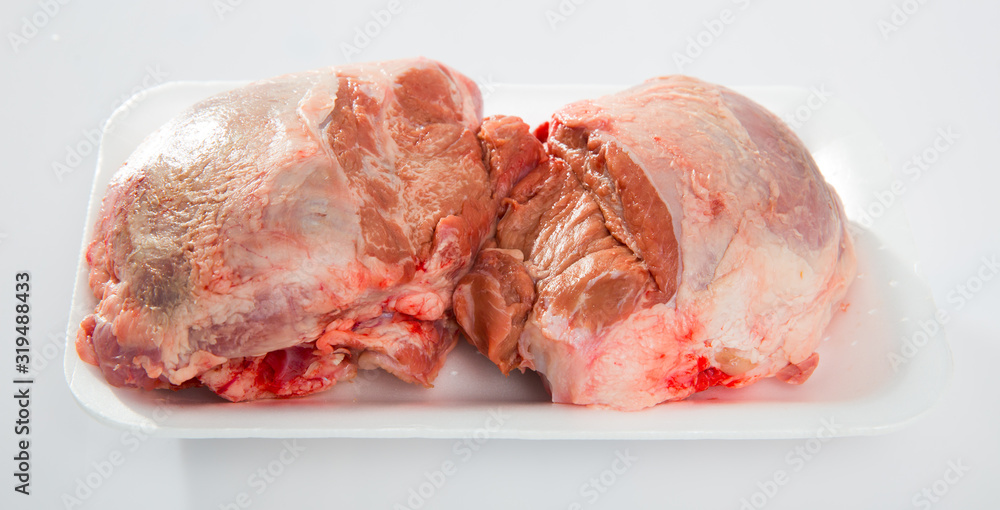 Close up of raw pig's cheeks on white table, nobody