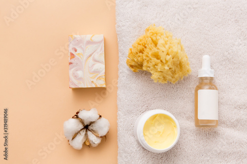 beauty  spa and wellness concept - close up of crafted soap bar  body butter  natural sponge and essential oil on bath towel