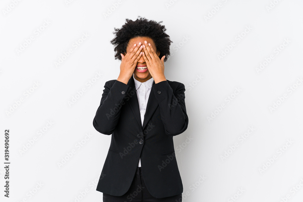 Middle aged african american business woman against a white background isolated covers eyes with hands, smiles broadly waiting for a surprise. Middle aged african american business woman against a white background isolated covers eyes with hands, smiles broadly waiting for a surprise.