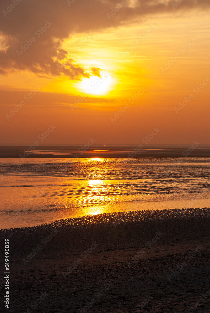France. Baie de Somme. Coucher de soleil sur l'océan et une plage de sable à marée basse.  Sunset over the ocean and a sandy beach at low tide.