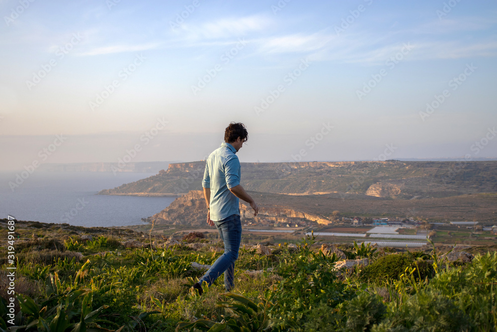 man walking in beautiful scenery watching an amazing view at the island Malta