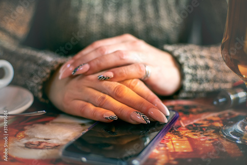 Woman's hands with manicured nails holding smartphone in the cafe