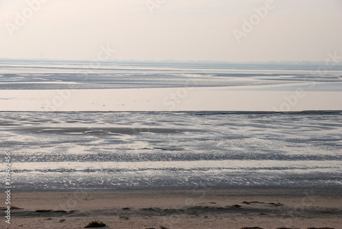 France. Baie de Somme. promeneur sur la plage de sable    mar  e basse sous le soleil. walker on the sandy beach at low tide under the sun.