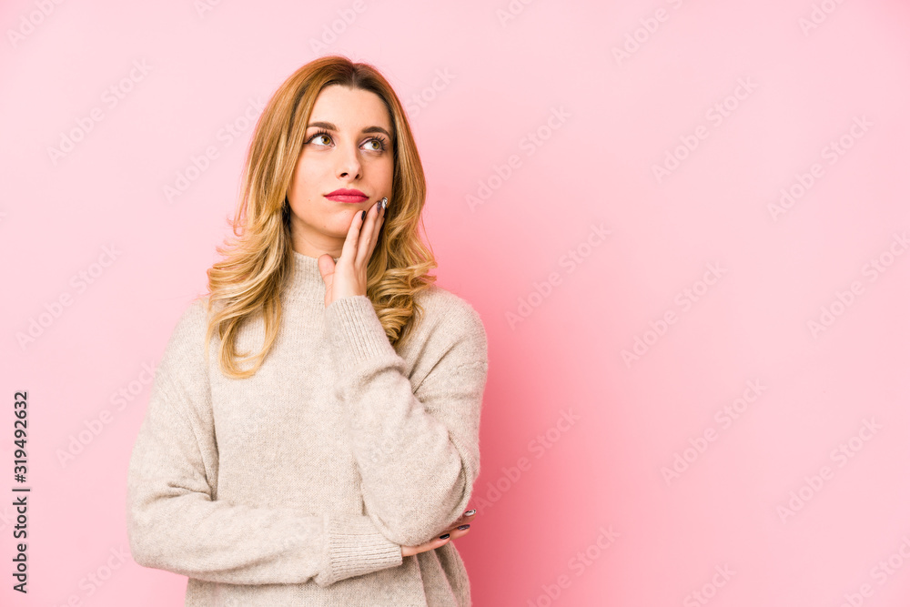 Young blonde cute woman wearing a sweater isolated looking sideways with doubtful and skeptical expression. Young blonde cute woman wearing a sweater isolated looking sideways with doubtful and skeptical expression.