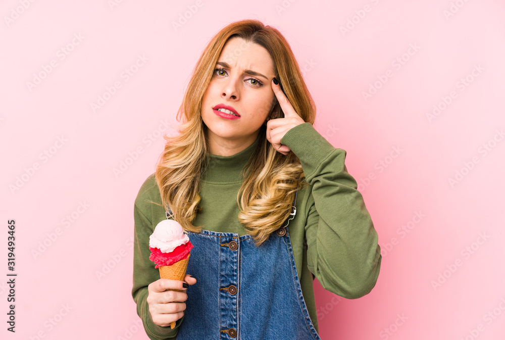 Young blonde woman eating an ice cream isolated showing a disappointment gesture with forefinger. Young blonde woman eating an ice cream isolated showing a disappointment gesture with forefinger.