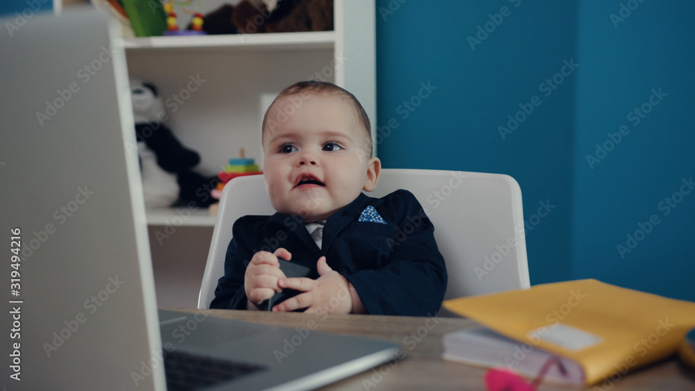 Close up view of extremely cute baby boss sitting in the office and smiling. Happy childhood, little cuteness, proud parents. Child’s portrait. Joke concept, positive emotions, feeling good