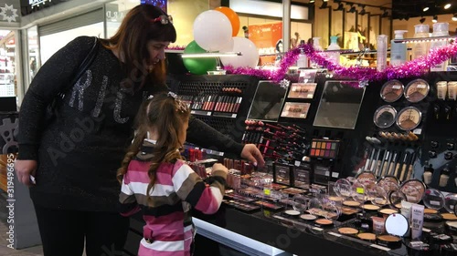 A Girl Kid chose cosmetics lipsticks, eye shadows in a Store