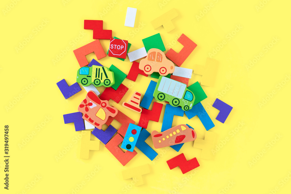 Obraz premium Colorful developing wooden blocks and handmade cars on yellow background. Natural, eco-friendly wooden toys for children. Top view. Flat lay. Copy space.