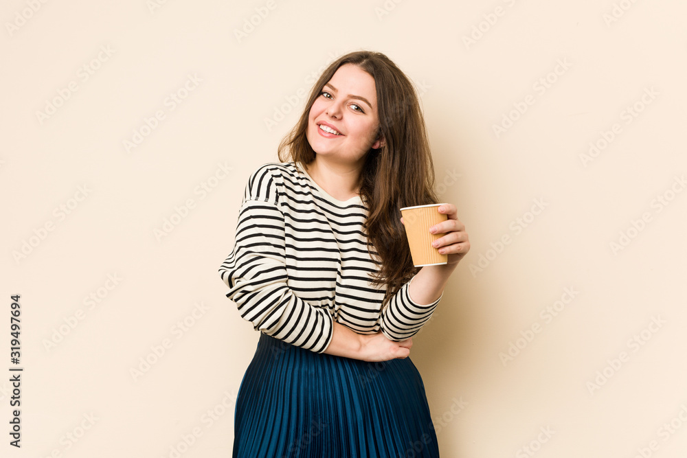Young curvy woman holding a coffee laughing and having fun. Young curvy woman holding a coffee laughing and having fun.