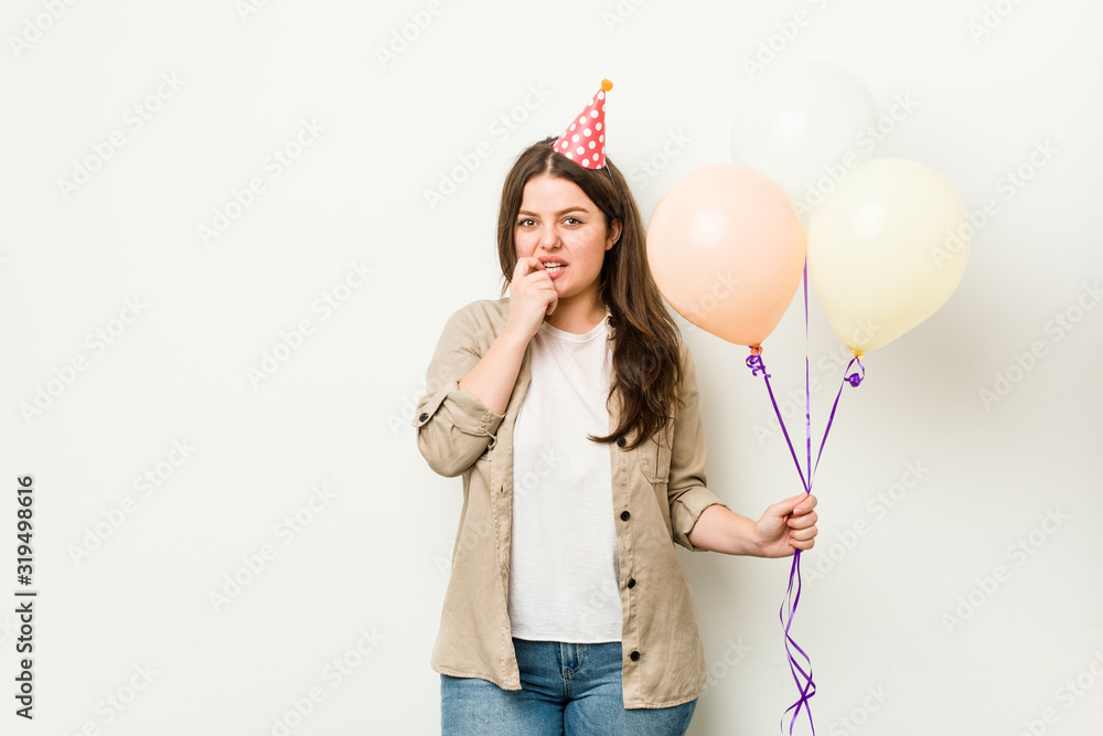 Young plus size curvy woman celebrating a birthday biting fingernails, nervous and very anxious.
