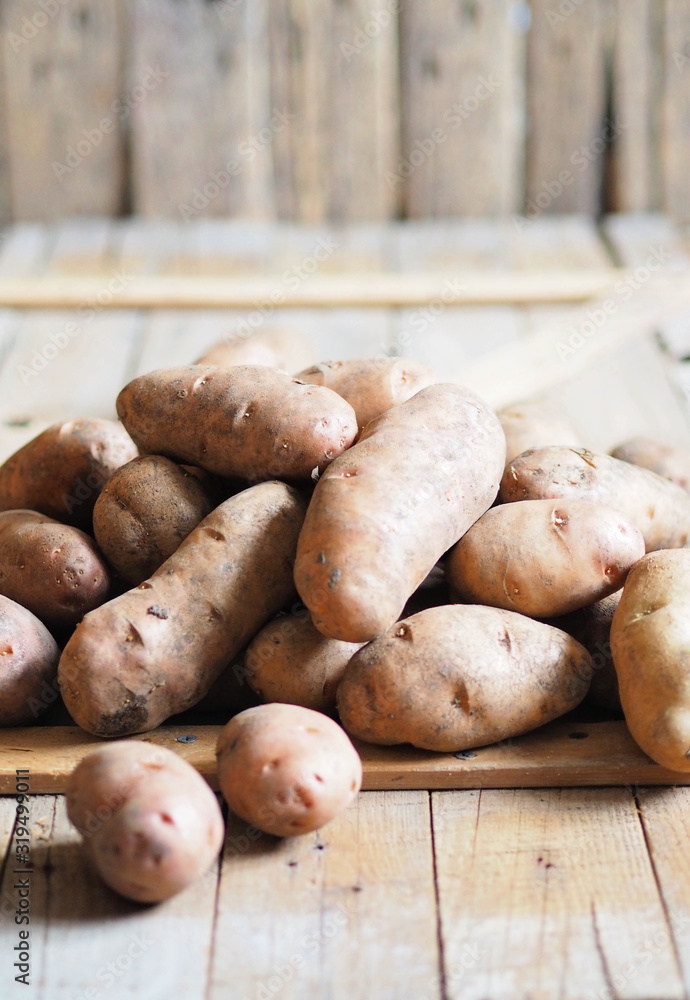Potato tubers on a wooden background close-up. Storage of potatoes in a wooden box. Potato tubers on a wooden background close-up. Storage of potatoes in a wooden box.