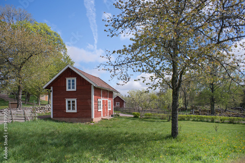 Countryside living idyll - Rural Swedish idyllic landscape in springtime - Red painted houses and plowed fields in the travel destination Asens By in Smaland Sweden. 