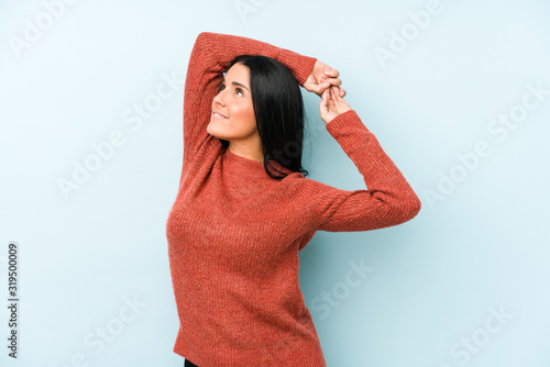 Young caucasian woman isolated on a blue background stretching arms, relaxed position. © Asier