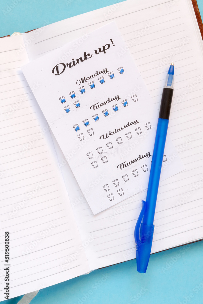 Water tracker, a womans hand notes the number of drinking glasses of water in the habits tracker, the idea of a healthy lifestyle and metabolism Water tracker, a womans hand notes the number of drinking glasses of water in the habits tracker, the idea of a healthy lifestyle and metabolism