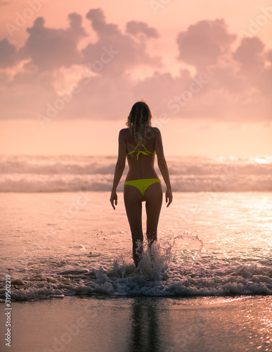 Slender female Silhouette on a background of sea waves and the sky with the setting sun
