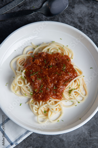 Spaghetti tomato sauce, sprinkled with coriander on a white plate, placed on a blue and white stripe. Look appetizing.