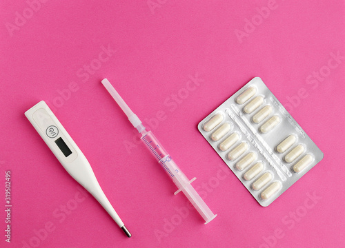 Thermometer  syringe  pills on a pink background