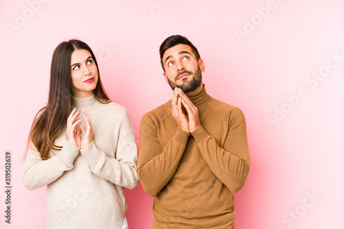 Young caucasian couple isolated making up plan in mind, setting up an idea.