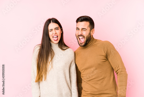Young caucasian couple isolated funny and friendly sticking out tongue.