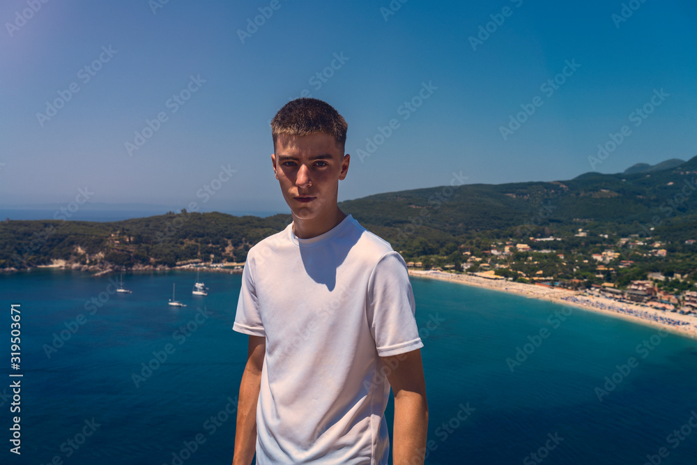 portrait of a self-confident young man with the beach of the city of parga in the background