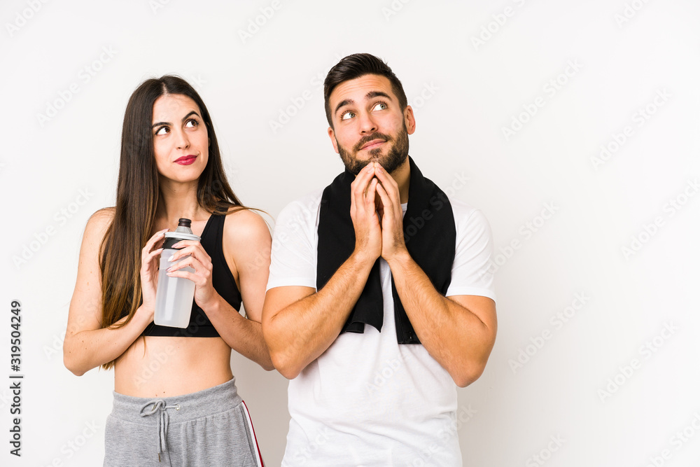 Young caucasian fitness couple isolated making up plan in mind, setting up an idea. Young caucasian fitness couple isolated making up plan in mind, setting up an idea.