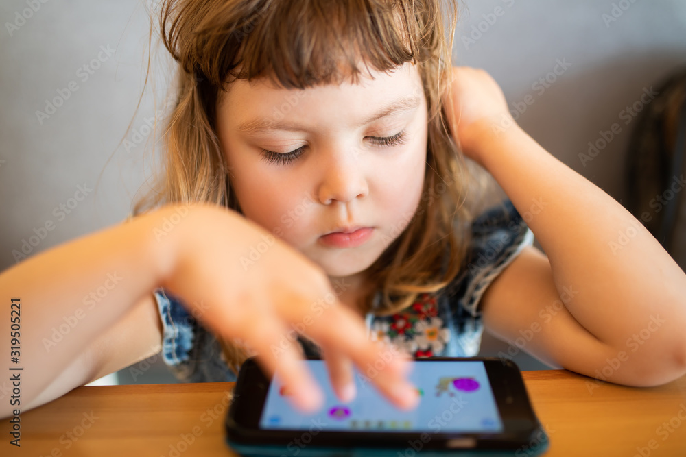 Little girl playing on her smartphone with a serious thoughtful face Little girl playing on her smartphone with a serious thoughtful face