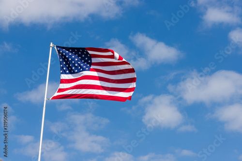 An American flag against a blue sky with clouds.