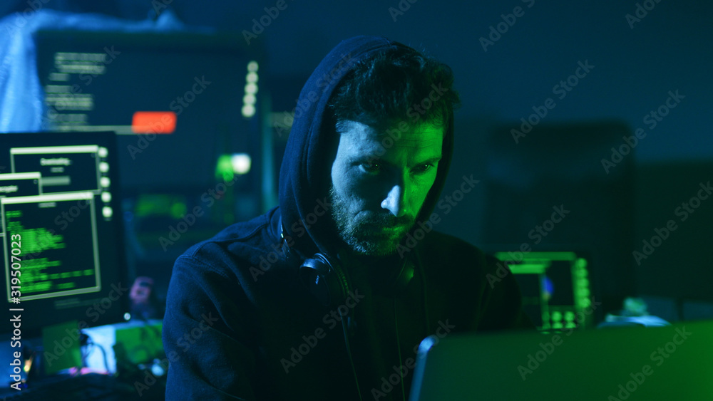 Close-up of experienced computer hacker at work. Portrait of concentrated young man looking at interface typing on keyboard in the office. Close-up of experienced computer hacker at work. Portrait of concentrated young man looking at interface typing on keyboard in the office.
