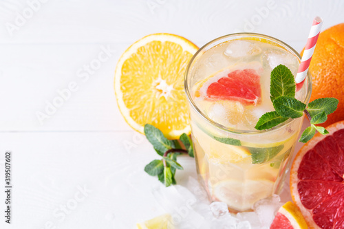 Summer refreshing lemonade with mint on a light background. A glass of citrus cocktail in a light key. Close-up. Summer Vitamin cocktail of orange, lemon and grapefruit.
