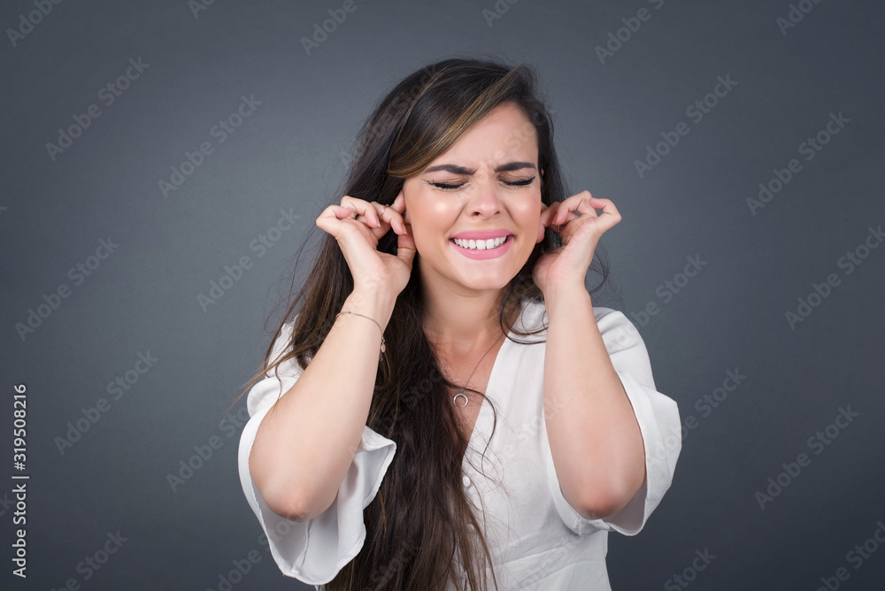 Stop making this annoying sound! Headshot of unhappy stressed out young female making wry face, plugging ears with fingers, irritated with loud noise coming from neighbours who live above her. Stop making this annoying sound! Headshot of unhappy stressed out young female making wry face, plugging ears with fingers, irritated with loud noise coming from neighbours who live above her.