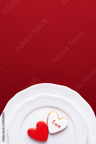 Two Valentine's cookies in shape of heart on white plates. Top view, concept of eating of love.