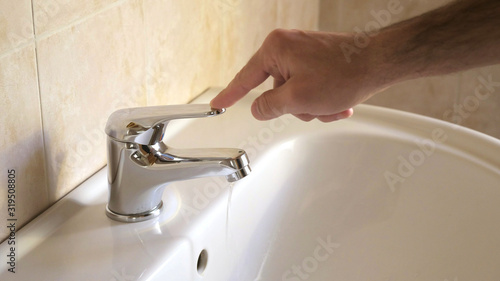 a person closes the water tap of the bathroom