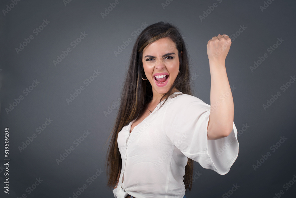 Fototapeta premium Overjoyed happy excited blonde female glad to receive good news, gestures actively from happiness, clenching fist and making winning gesture. Reaction concept.