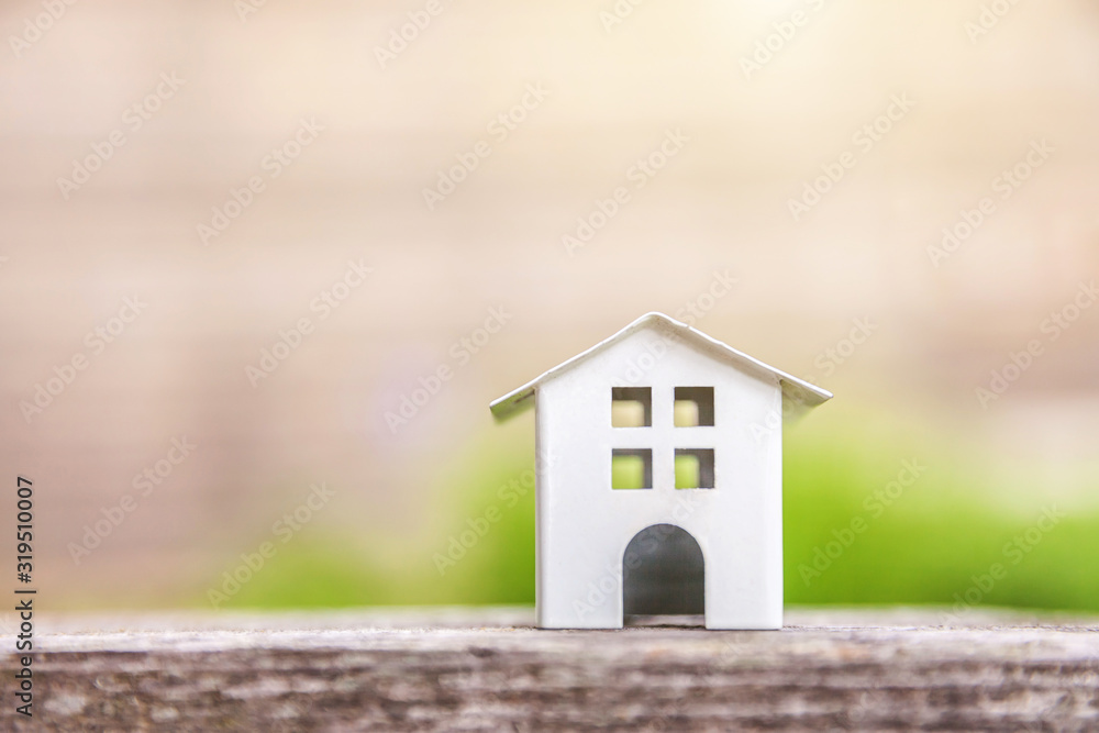 Miniature white toy model house in wooden background near green backdrop. Eco Village, abstract environmental background. Real estate mortgage property insurance dream home ecology concept Miniature white toy model house in wooden background near green backdrop. Eco Village, abstract environmental background. Real estate mortgage property insurance dream home ecology concept