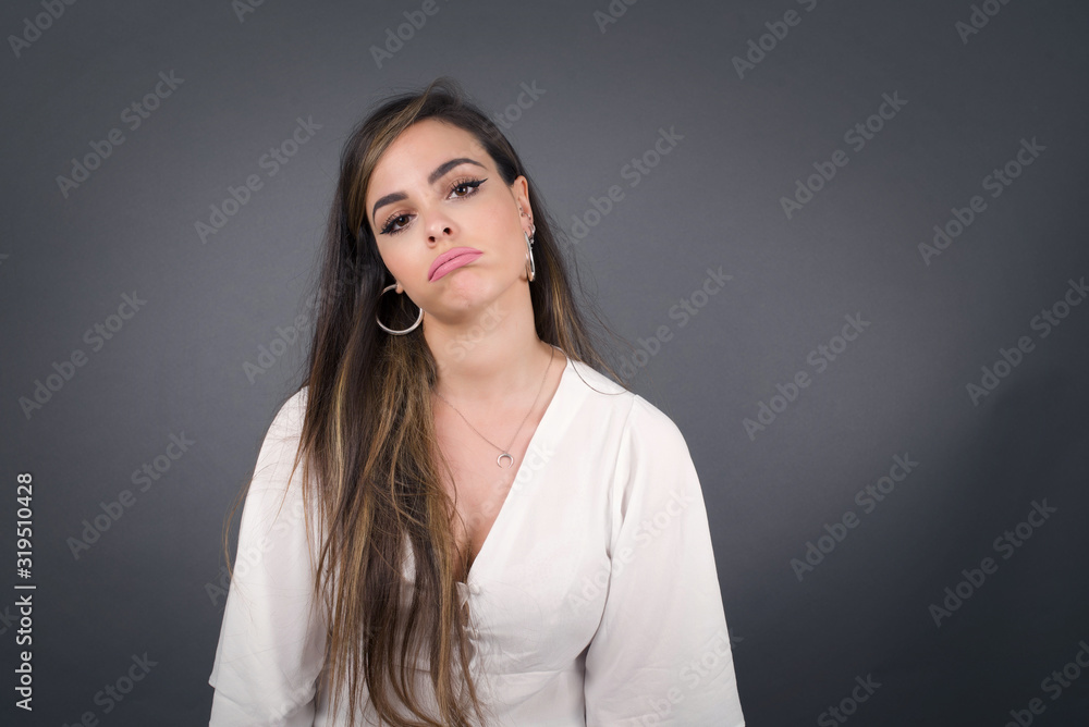 Gloomy, bored girl frowns face looking up, being upset with so much talking hands down, feels tired and wants to leave. Angry sullen woman standing indoors. Gloomy, bored girl frowns face looking up, being upset with so much talking hands down, feels tired and wants to leave. Angry sullen woman standing indoors.