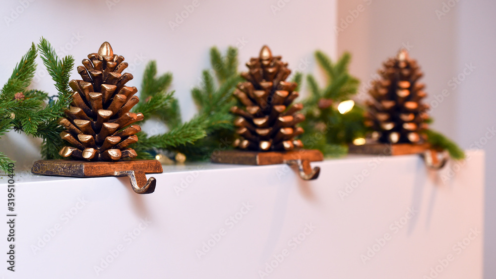 Three pine cone Christmas stocking holders on mantle